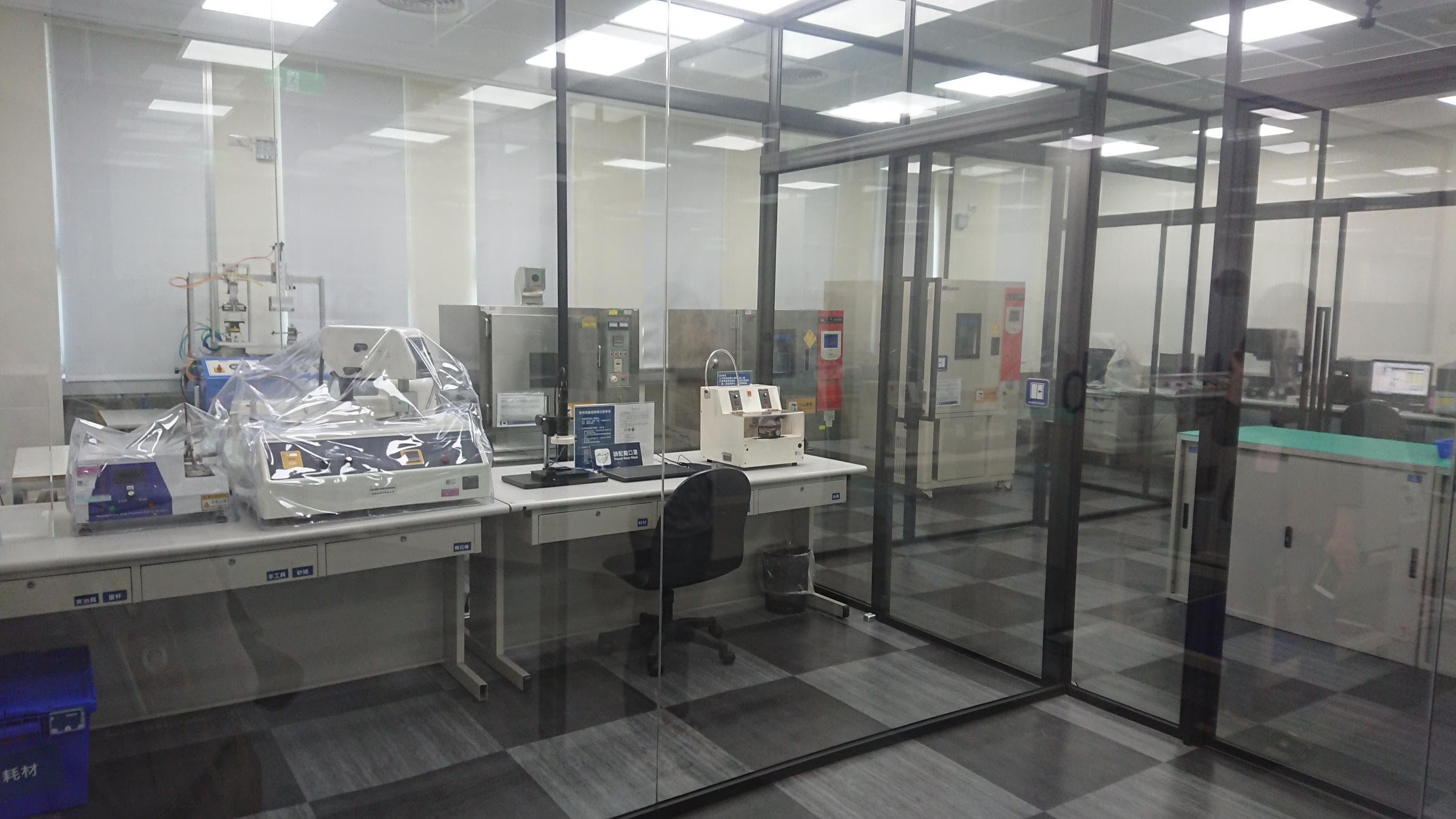 Radbon testing laboratory with workbenches and environmental test equipment behind glass partitions